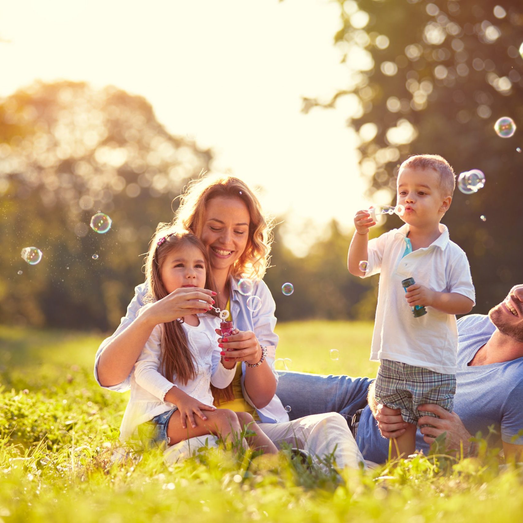 Family with children blow soap bubbles outdoor