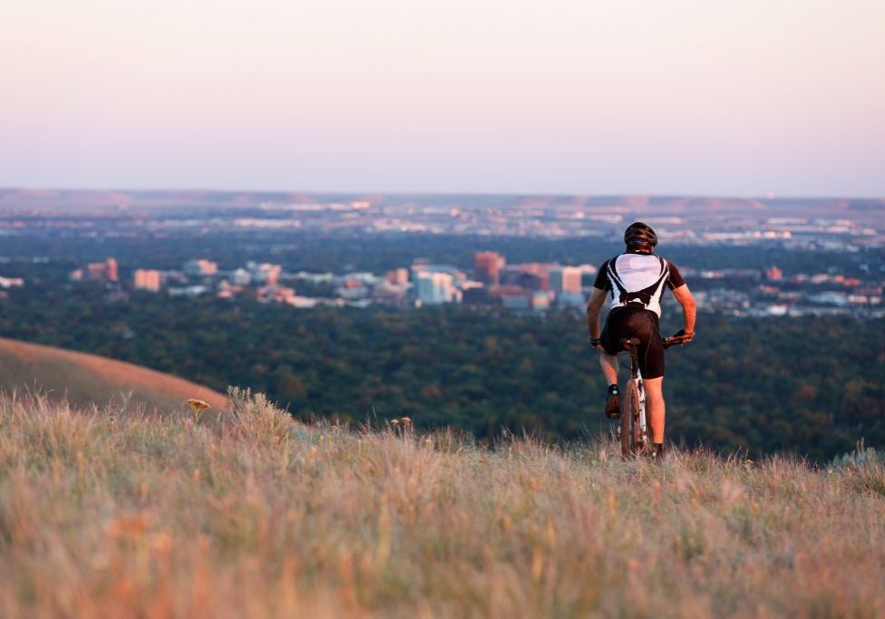 Man on mountain bike riding in the foothills, downtown Boise is visible in the distance