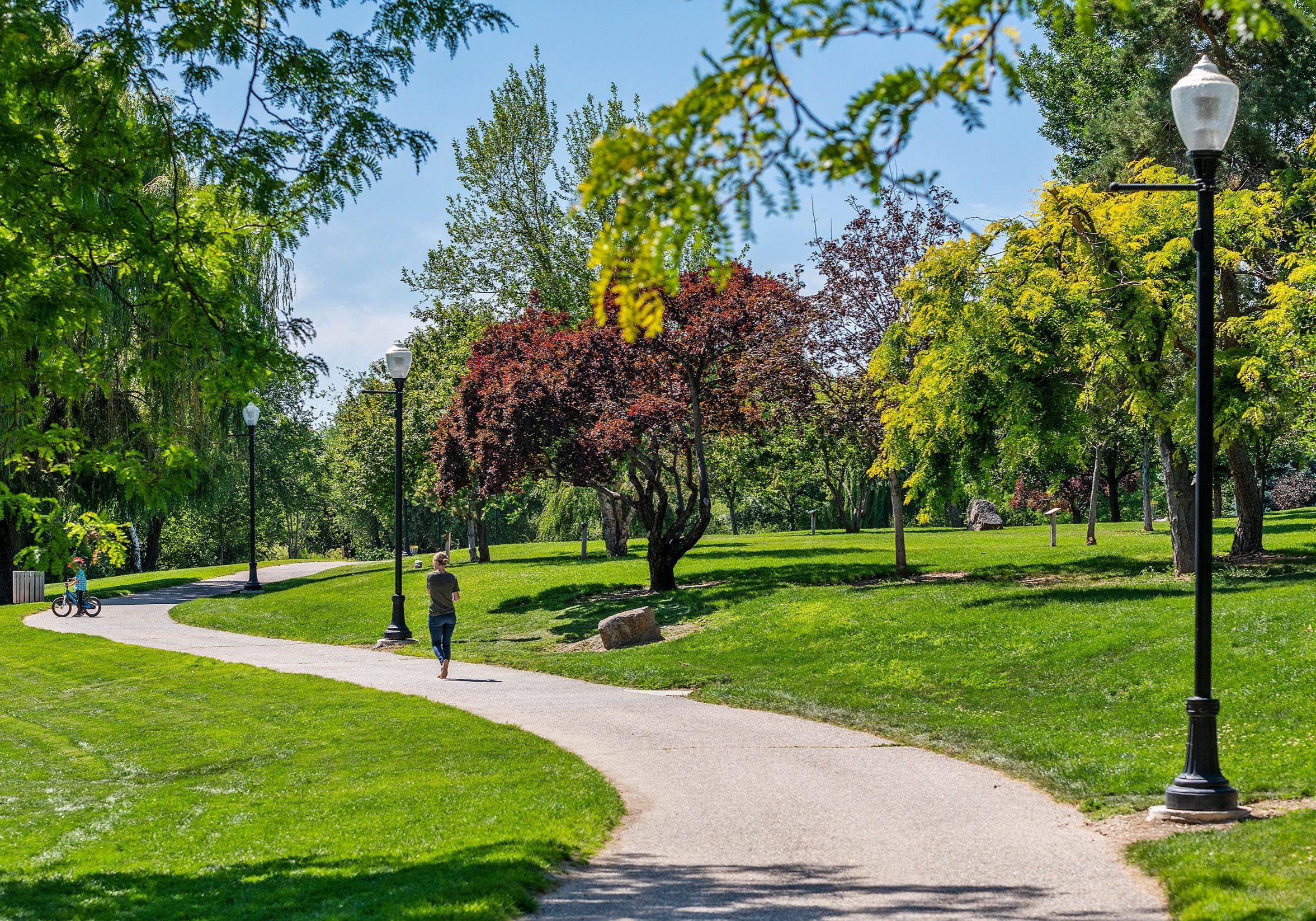 Curved walking path lined with street lamps, cutting through Indian Creek Park in Kuna Idaho