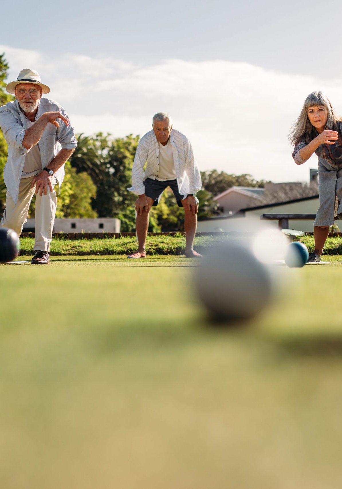 Senior man and woman playing boules competing with each other. Ground level shot of elderly people playing boules in a park with blurred boules in the foreground.